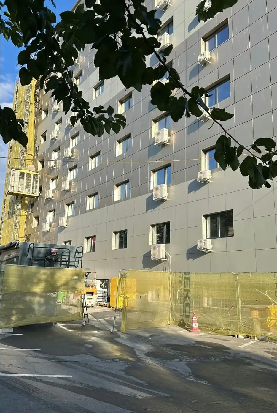 Aparat de aer condiționat montat pe un perete placat cu piatră decorativă, deasupra unei ferestre deschise prin care se văd unitățile exterioare